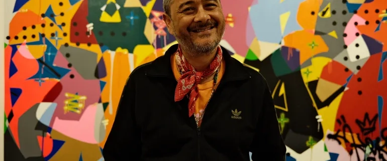 Cyril Kongo poses in front of one of his graffiti-style paintings at Art Jakarta [Jessica Washington/ Al Jazeera]